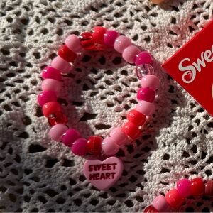 Sweet heart bracelet with red beads and pink heart .